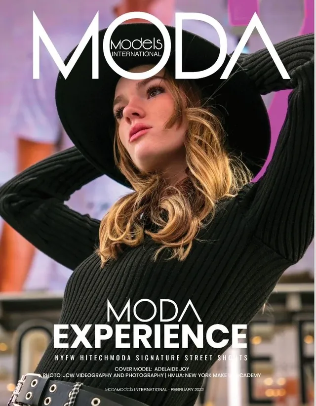 Cover of MODA Models International, February 2022: a model in a wide black hat and black sweater, arms raised.